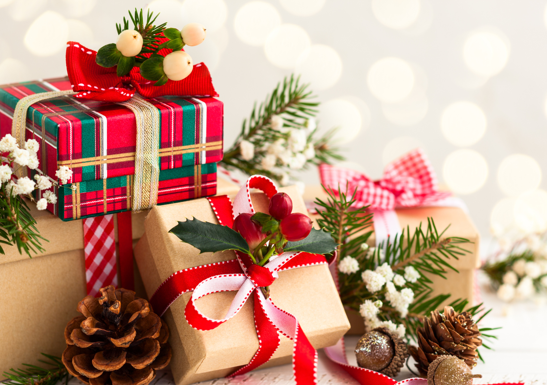 Festlich verpackte Geschenke mit Schleifen, Tannenzweigen, Zapfen und roten Beeren