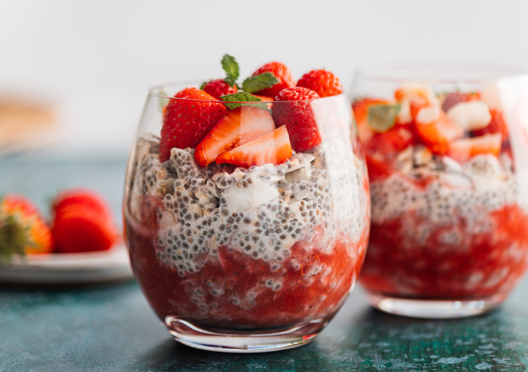 Leckerer Chia-Pudding geschichtet mit Erdbeeren und garniert mit Minze, serviert im Glas.