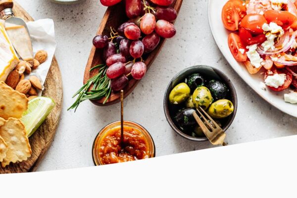 Auswahl an Convenience-Feinkost mit Käse, Aufschnitt, Oliven, Crackern und Tomatensalat – frisch angerichtet.