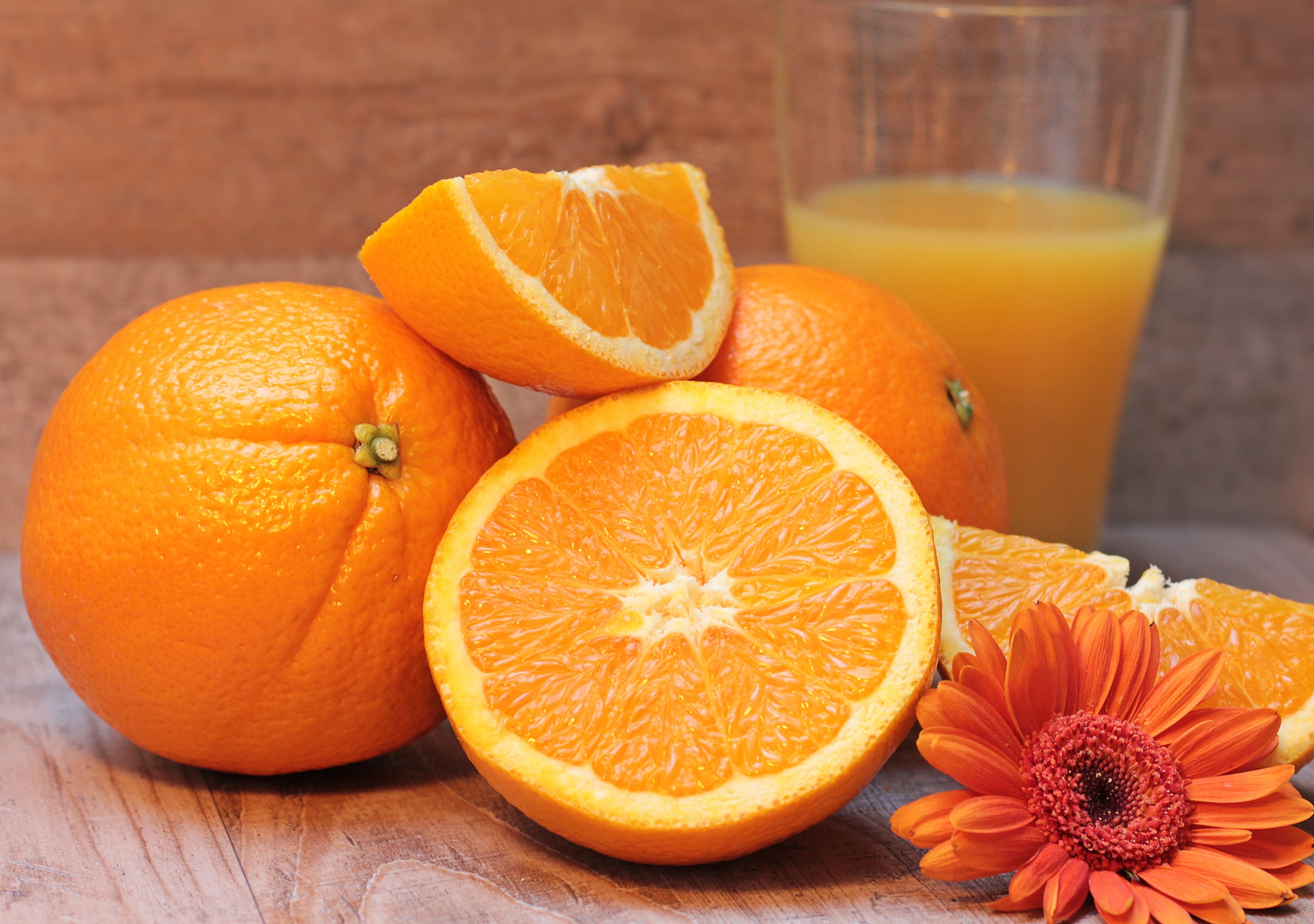 Frische, ganze und aufgeschnittene Orangen mit einem Glas Orangensaft